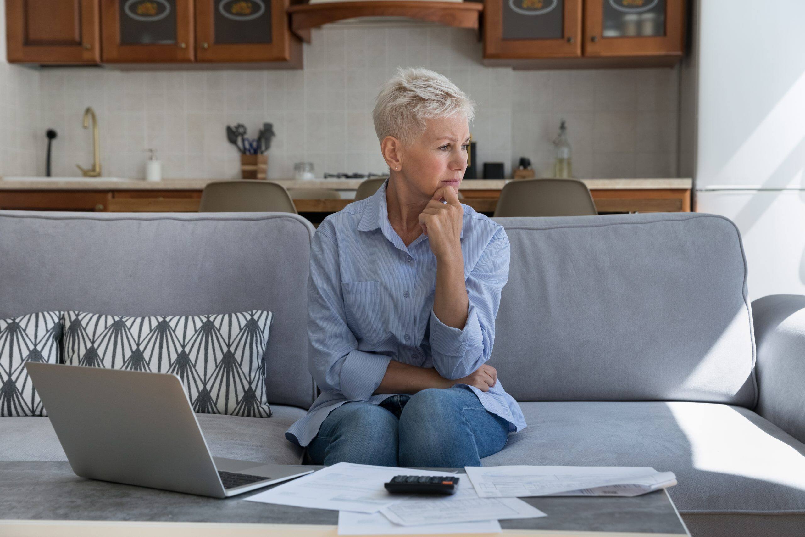 confused old lady sitting on the sofa thinking about how to invest