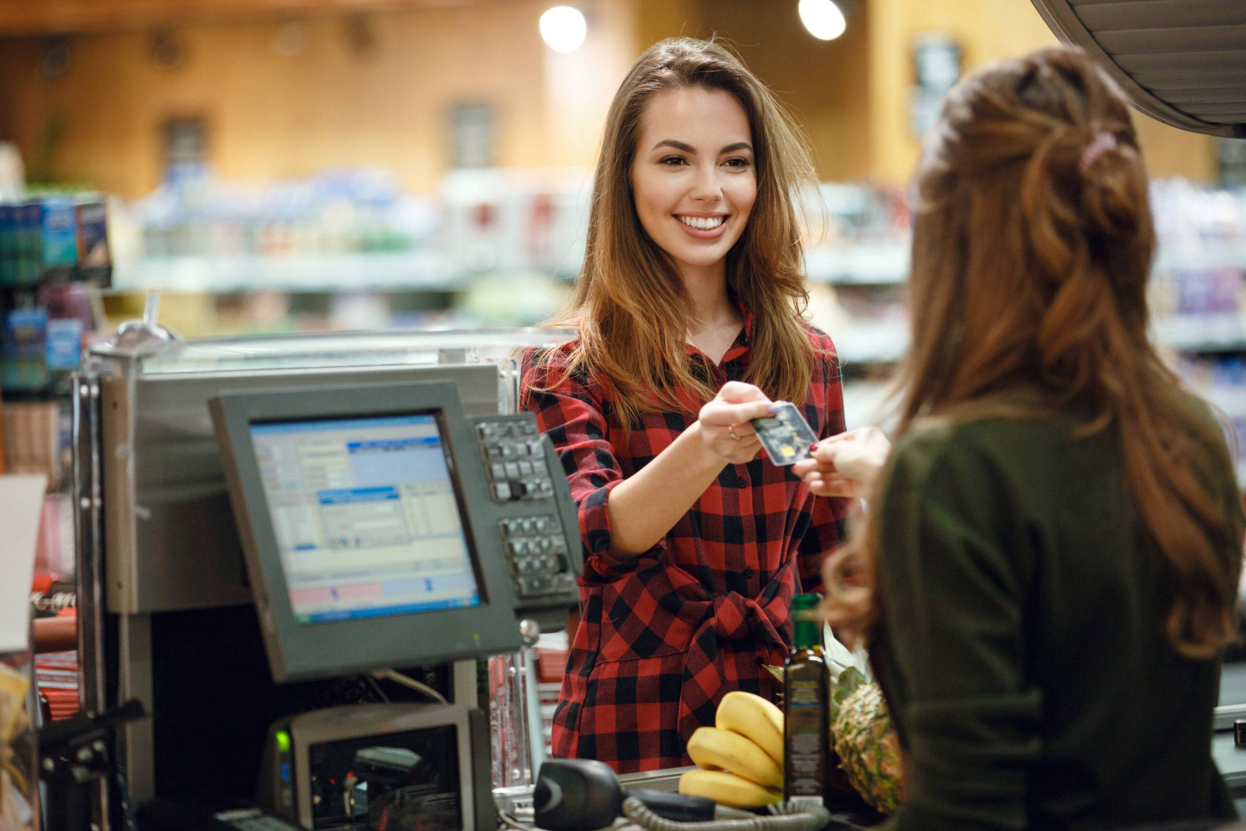 young lady using a debit card in supermarket