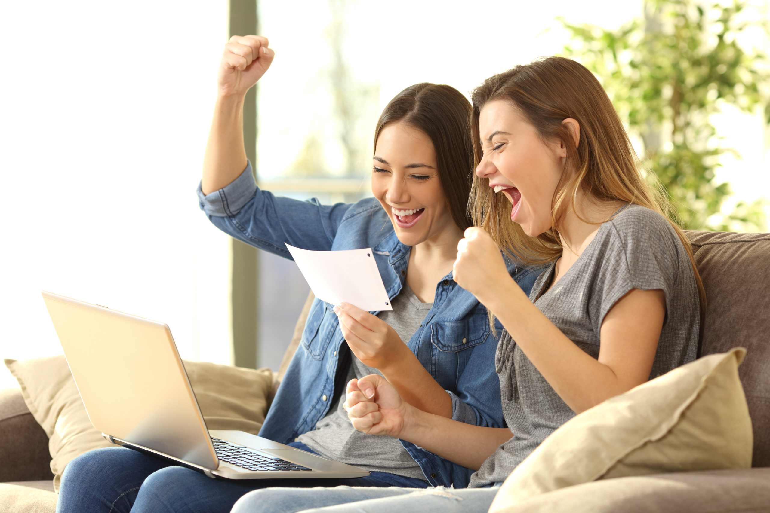 excited girls receiving free cash from bank sitting on a sofa