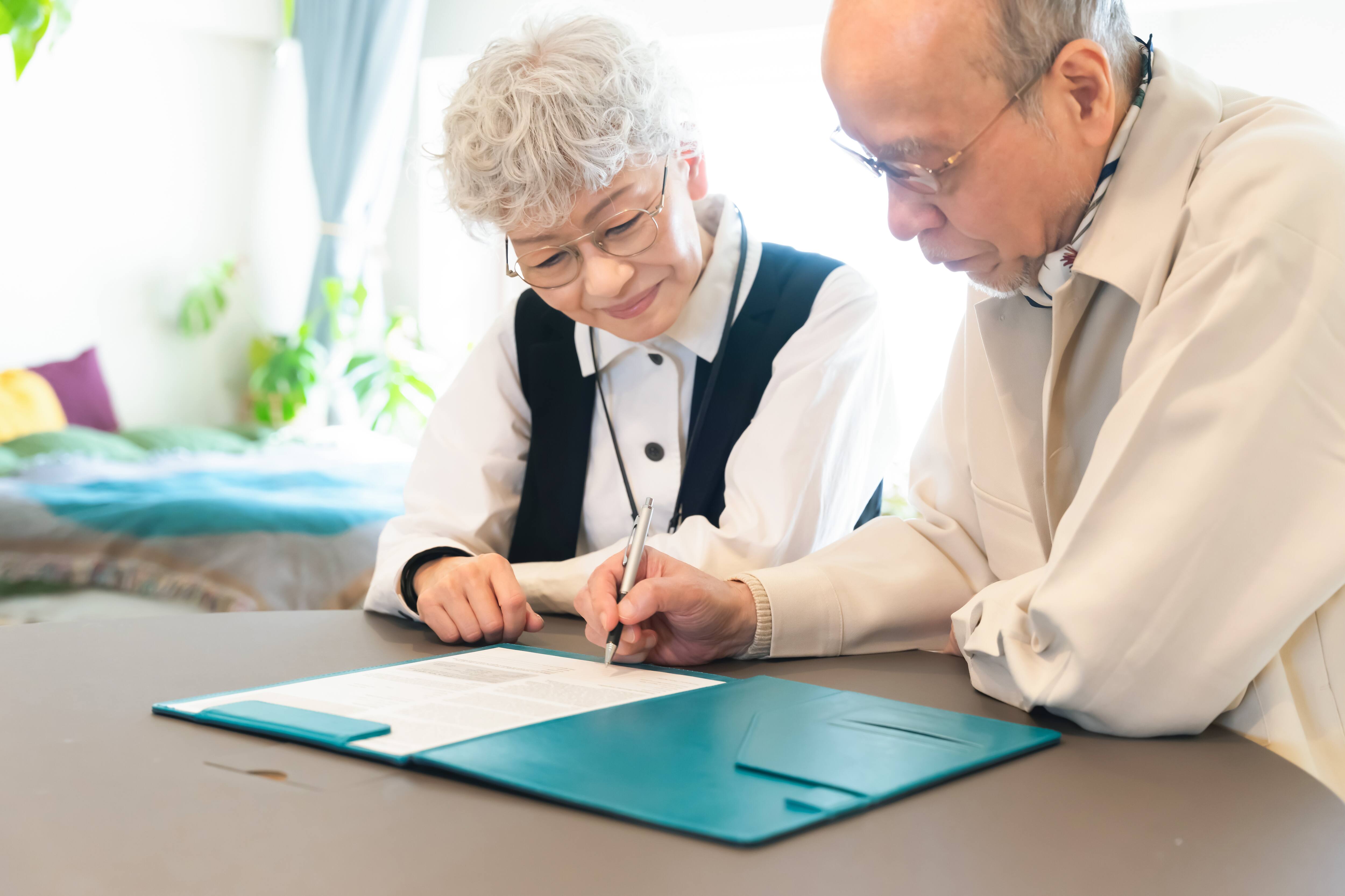 asian senior couple filling out paperwork for checking account