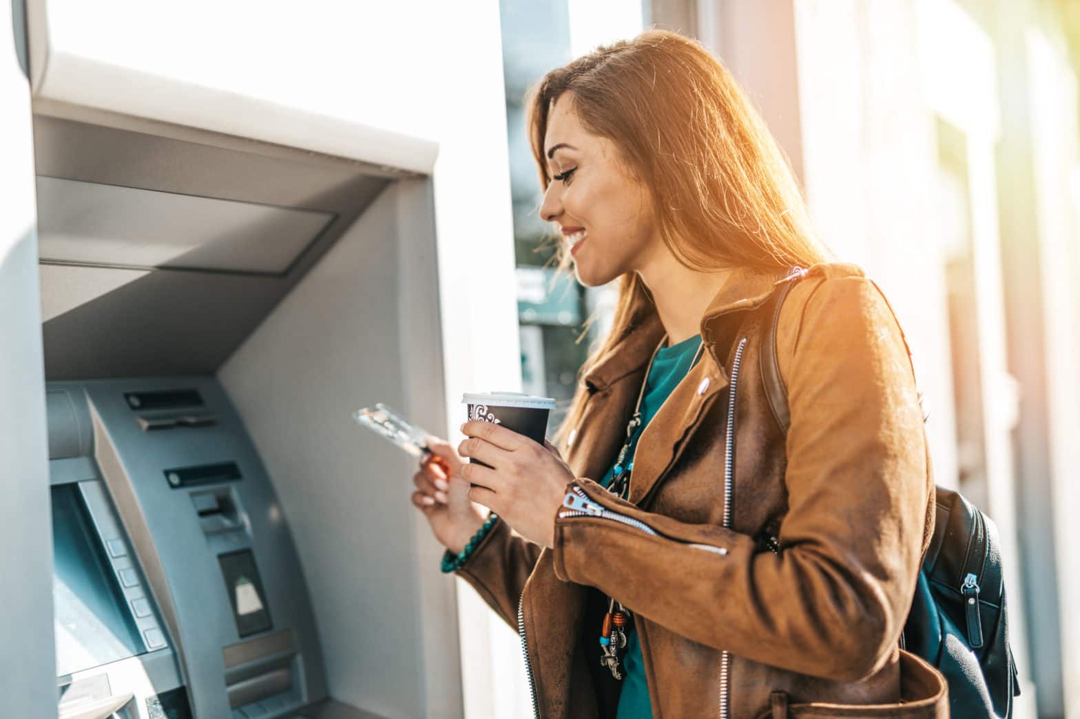 woman standing in front of an atm machine withdrawing cash