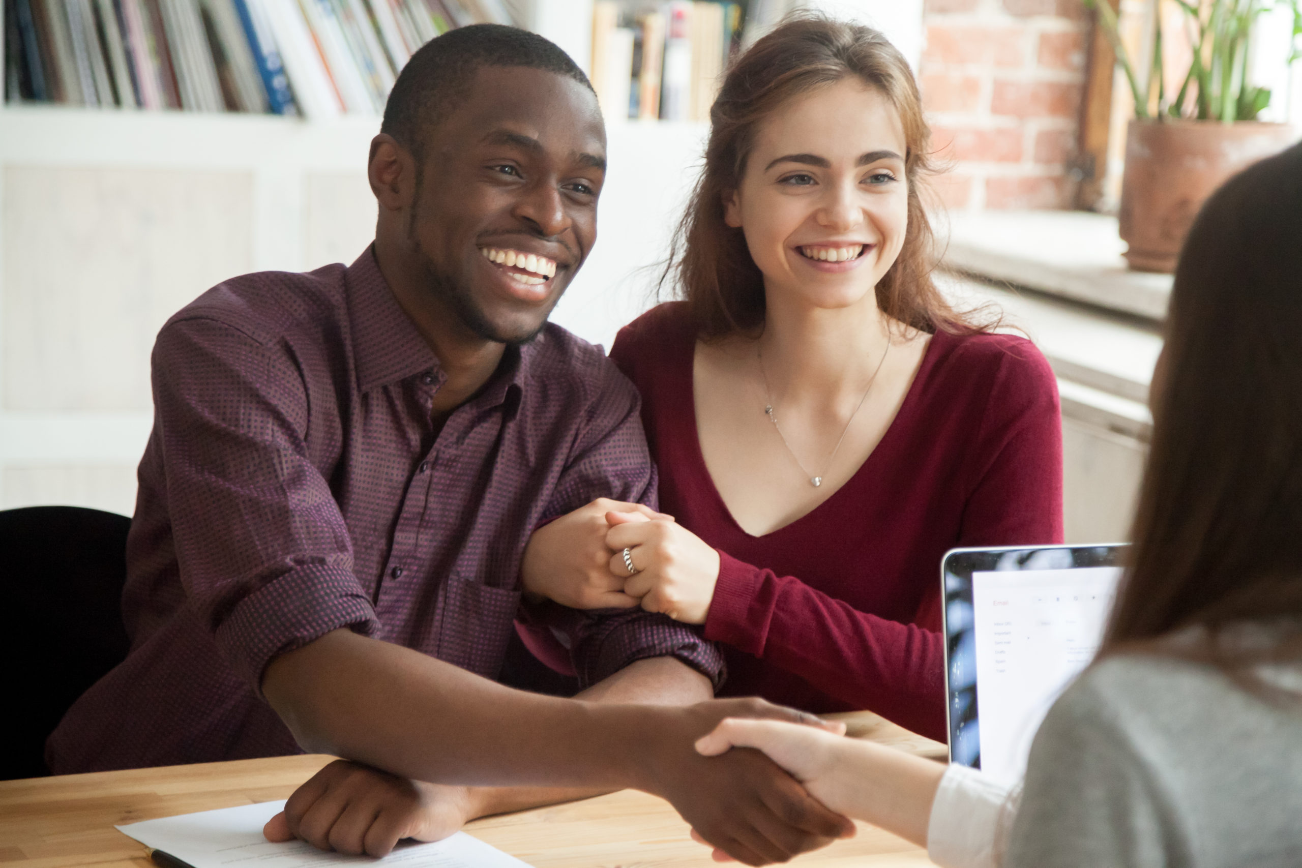 smiling couple customers shaking hands with agent