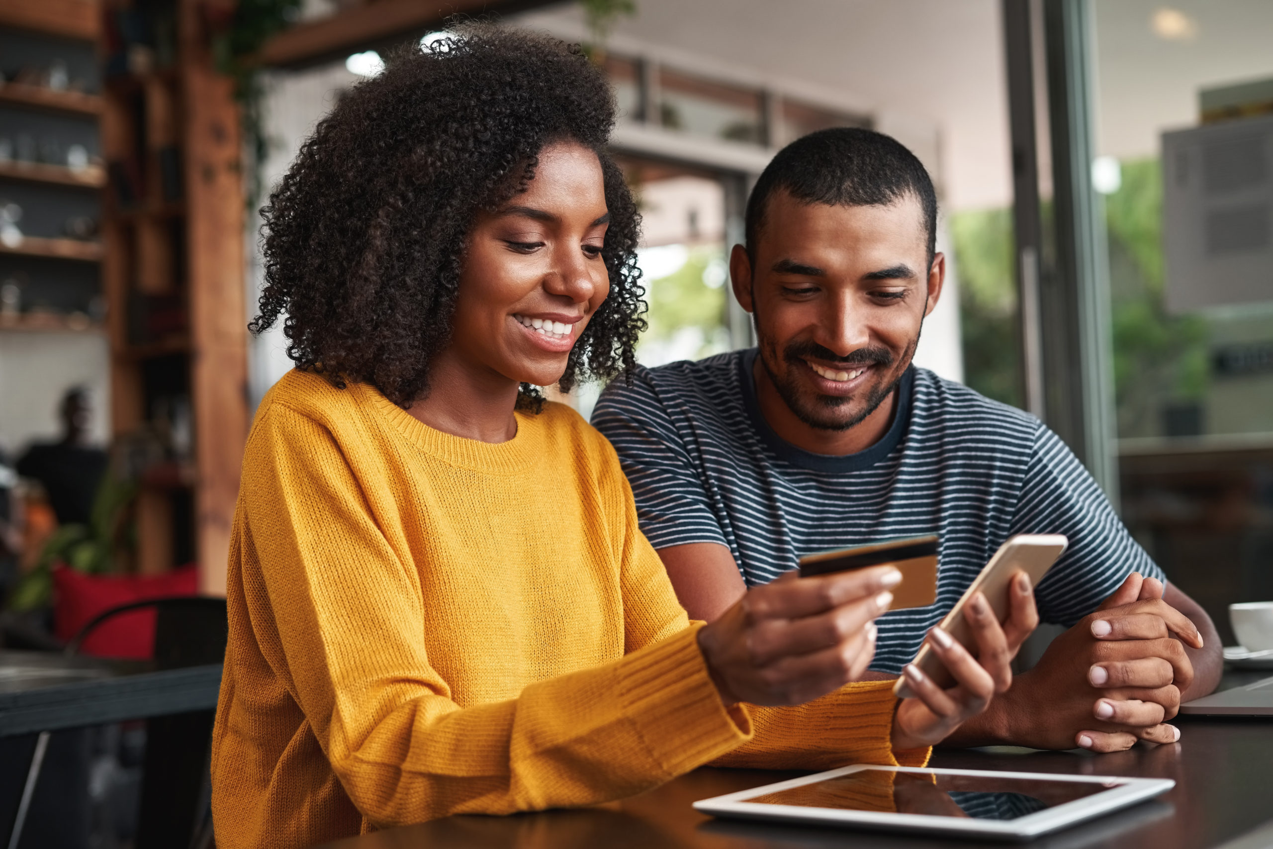 man looking at his girlfriend shopping online using credit card