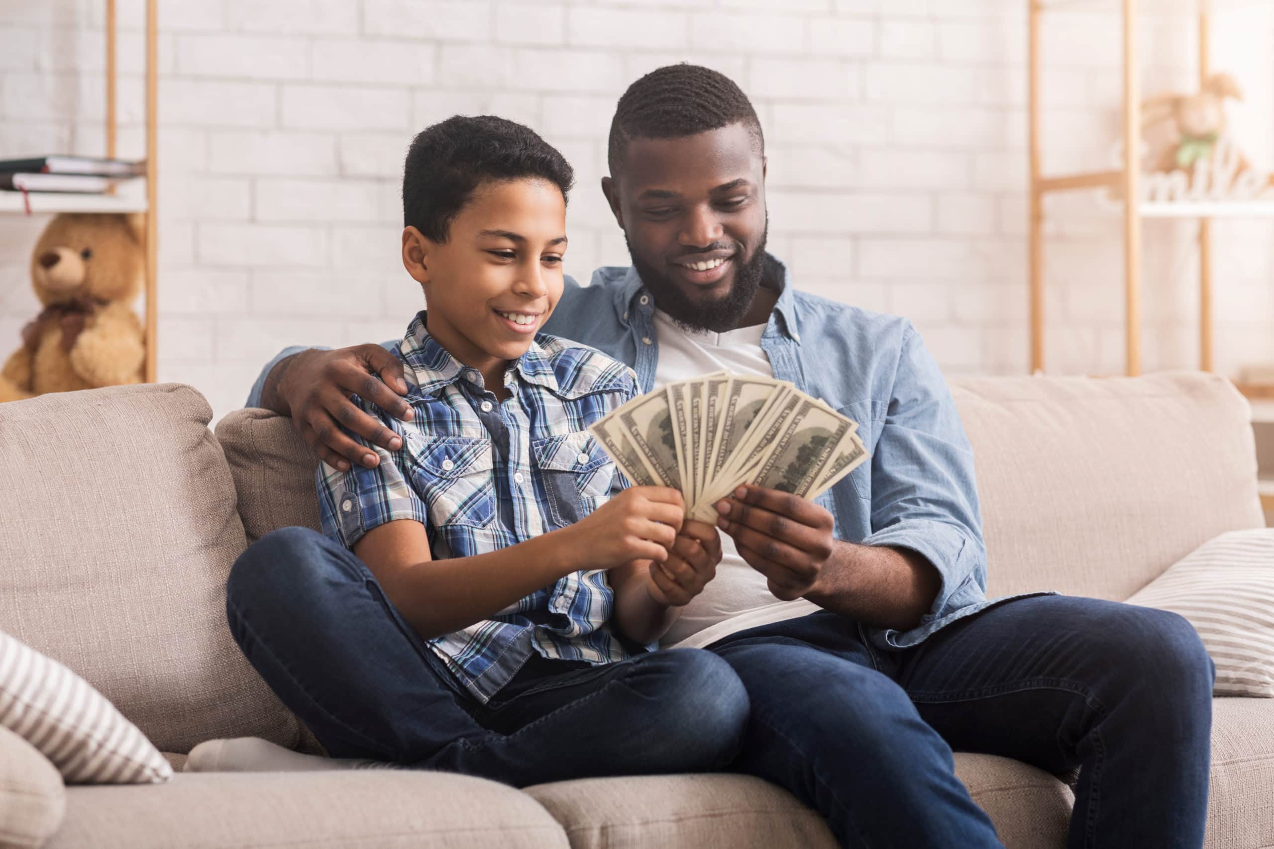man counting dollar cash with son explaining