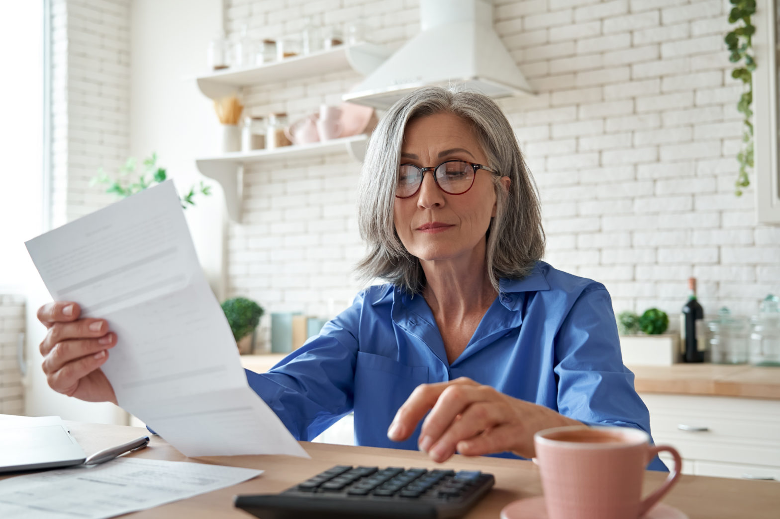 Woman holding documents and using the calculator