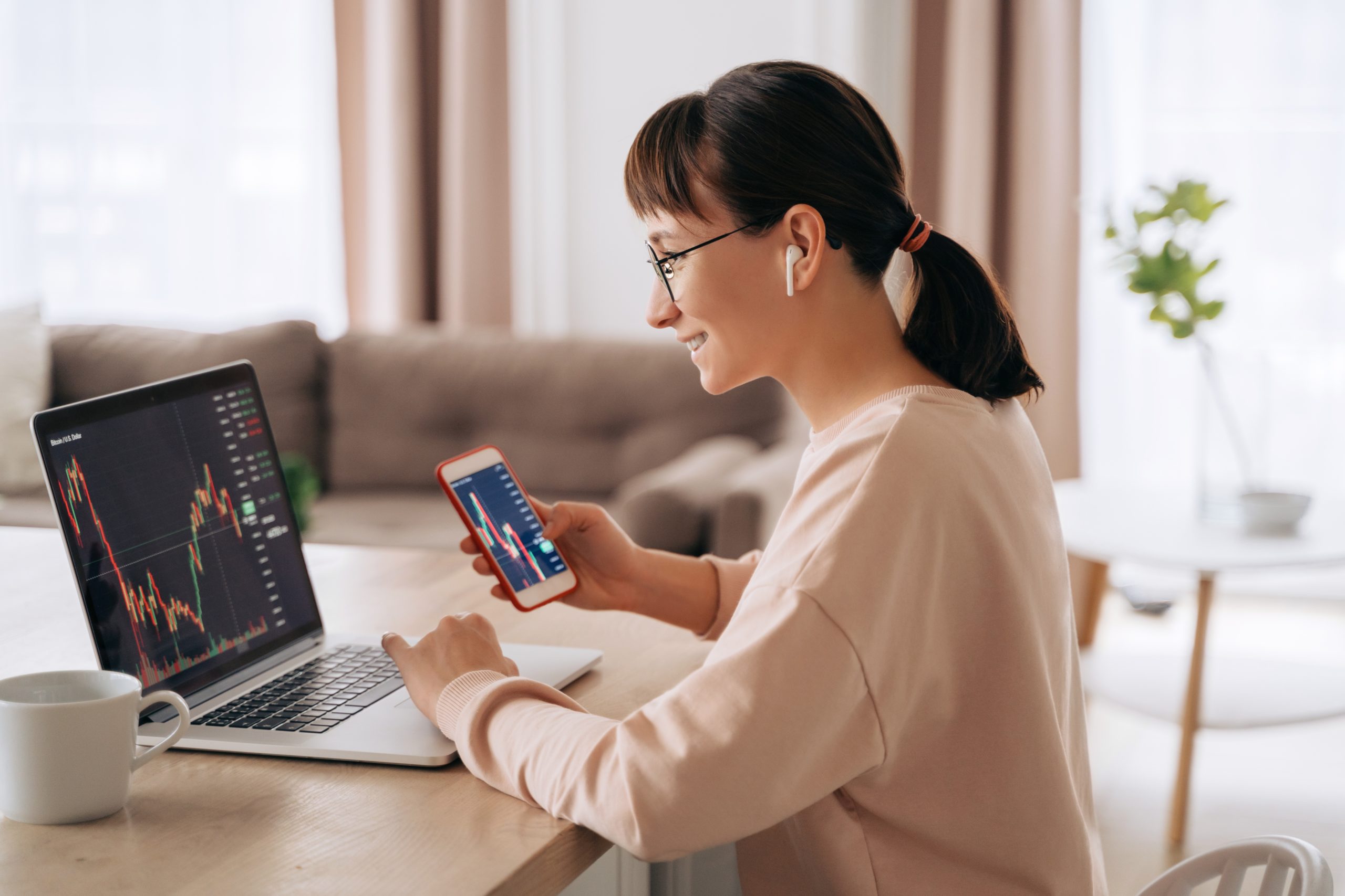 smiling woman trader analyzing stock at the laptop to invest