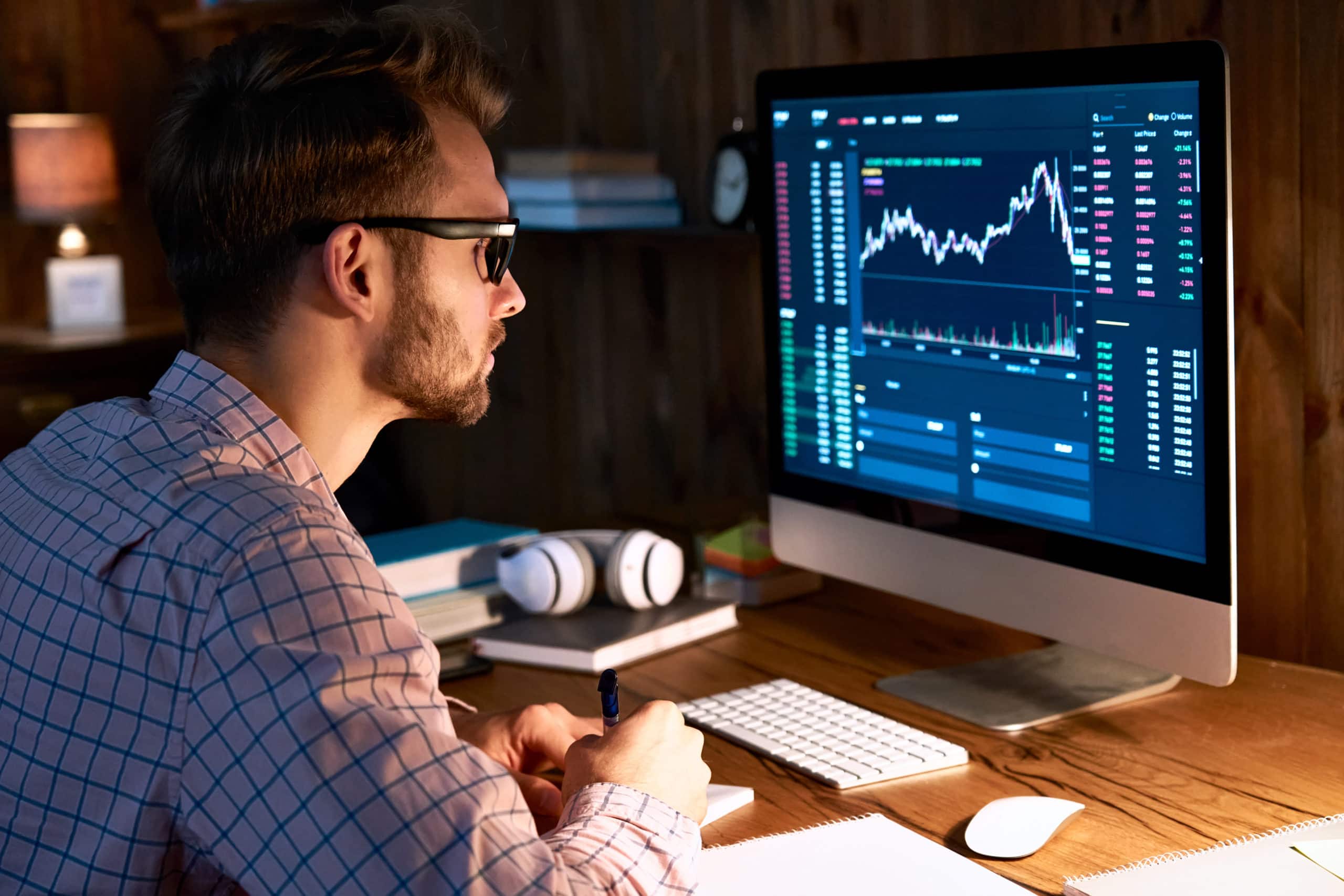 man trader analyst looking at desktop to read stocks