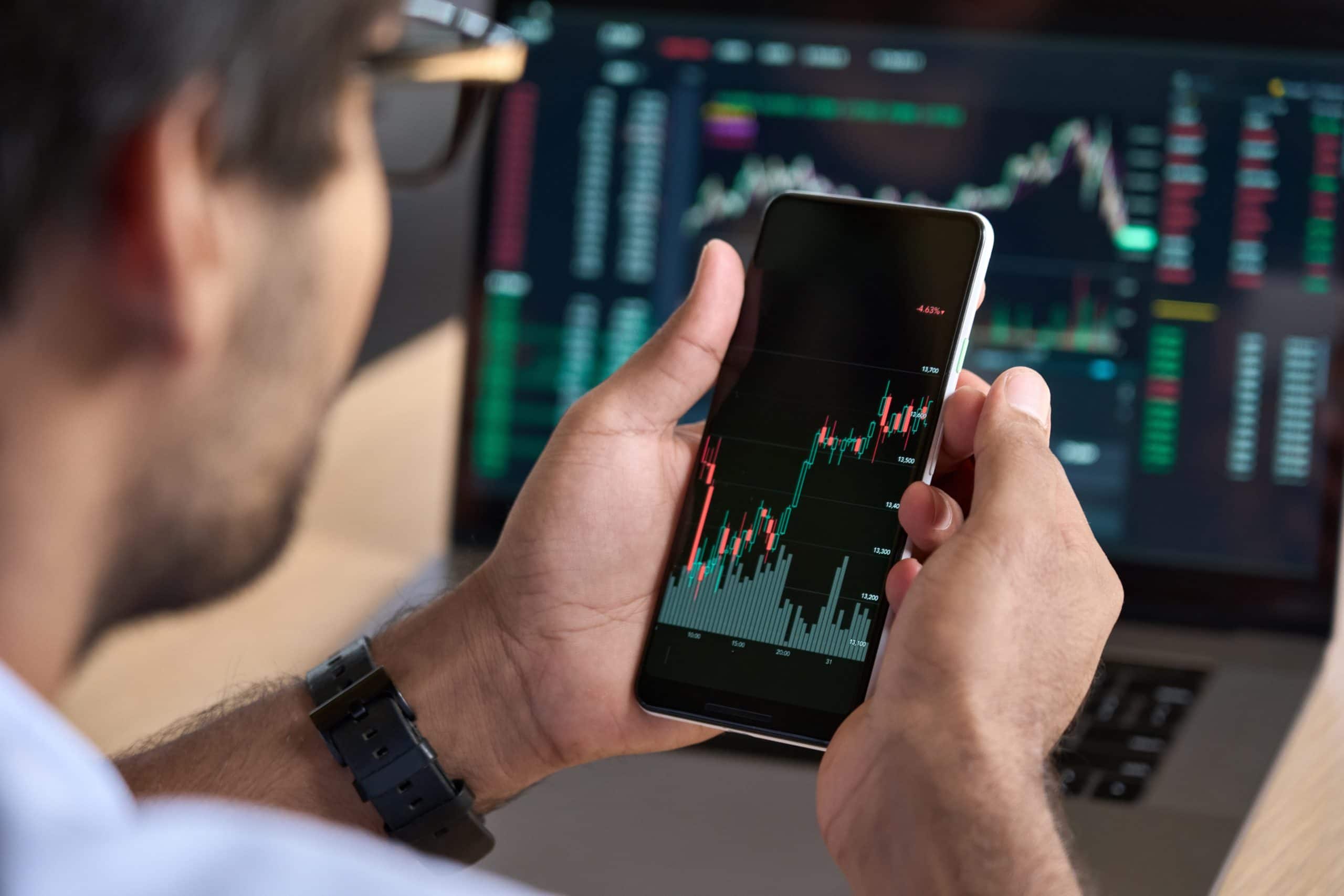 male trader investor holding smartphone in hand
