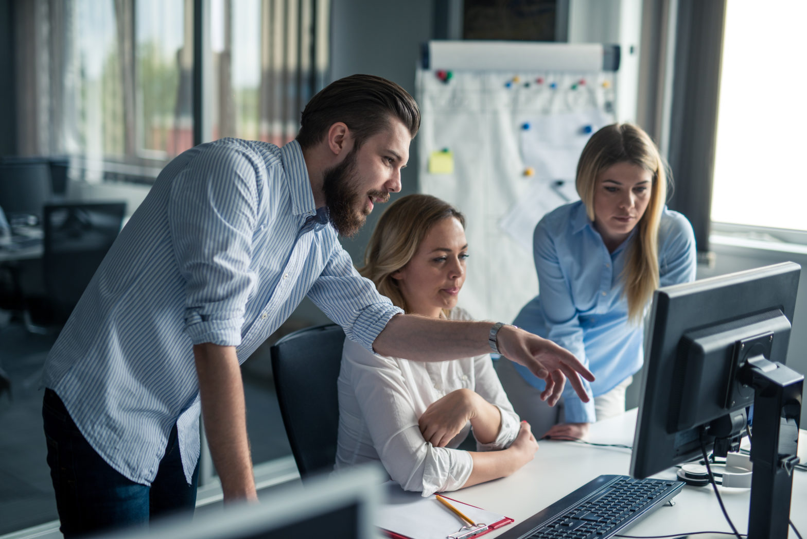 Coworkers looking at a computer and talking about 401k employer match