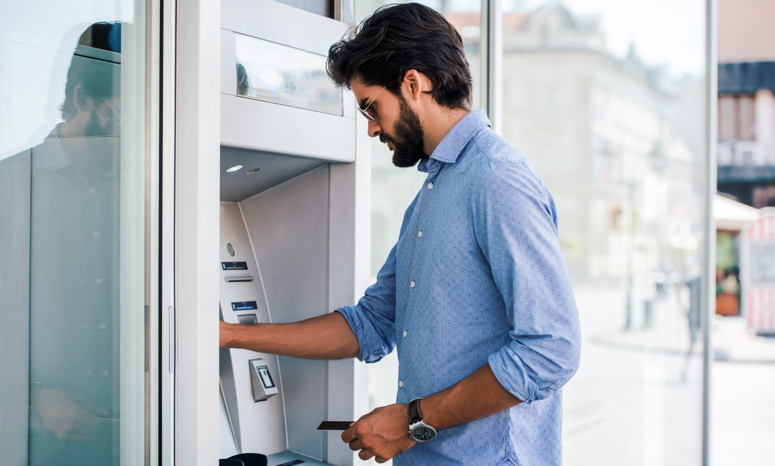 Man using a street ATM machine and withdrawing money