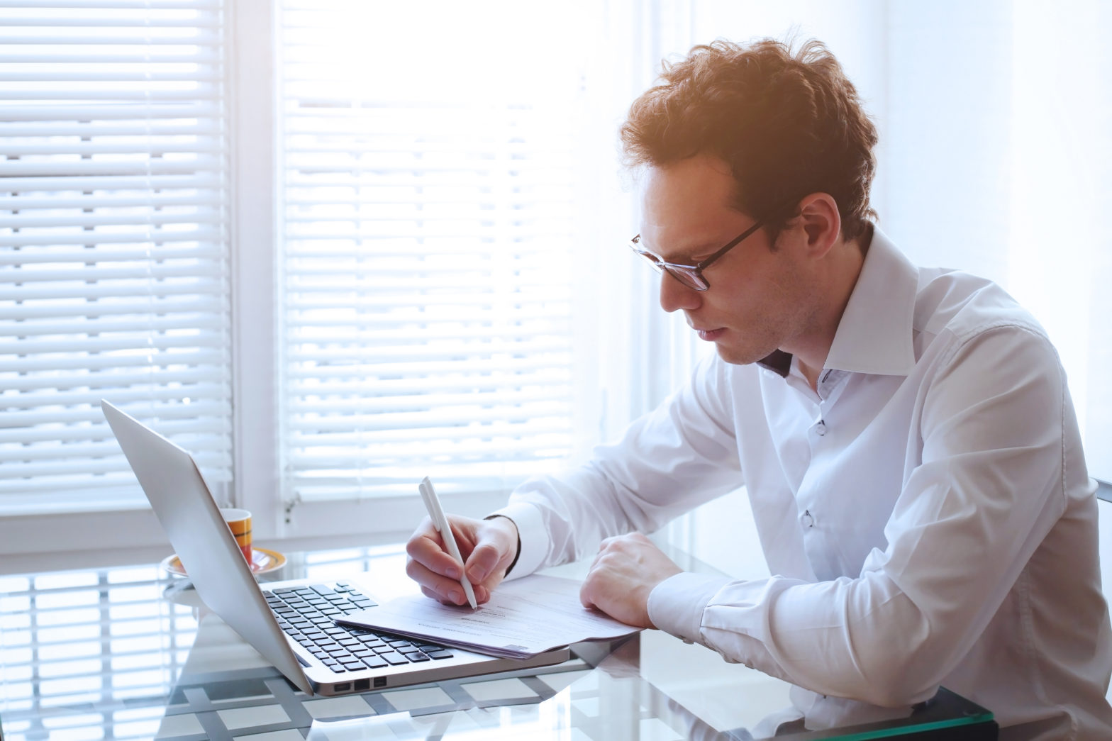 Man sitting at desk in front of laptop to calculate CD interest and taxes documents