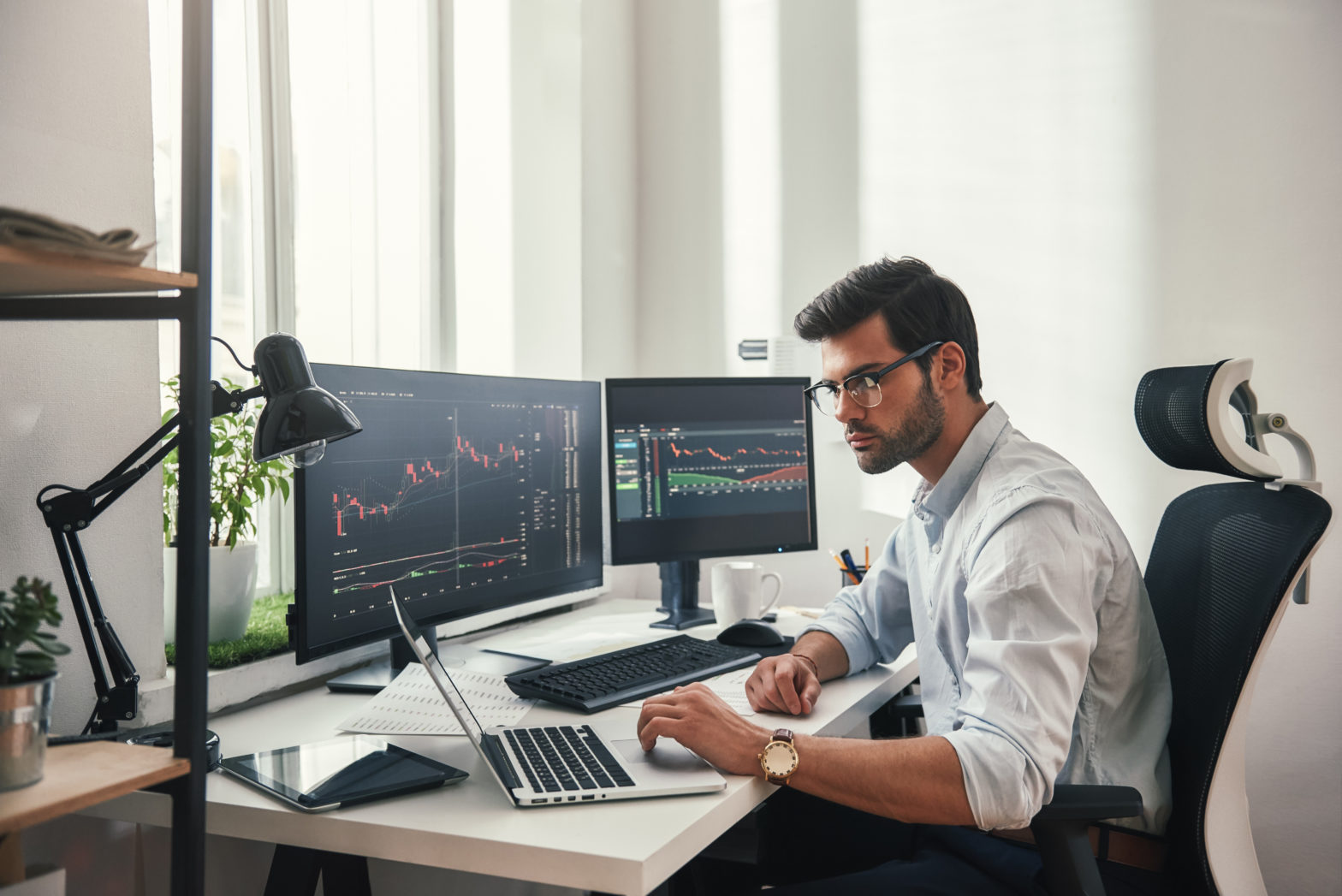 Young CD broker working with multiple desktops and laptops to check to trade