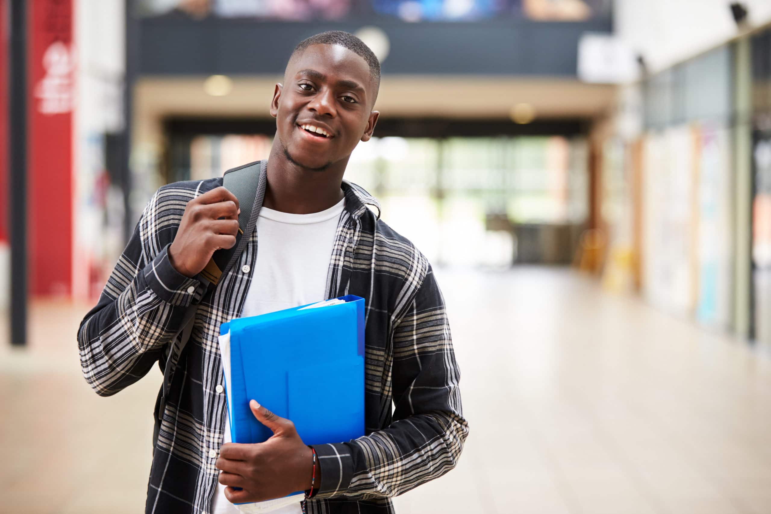 male student standing in college building debt free