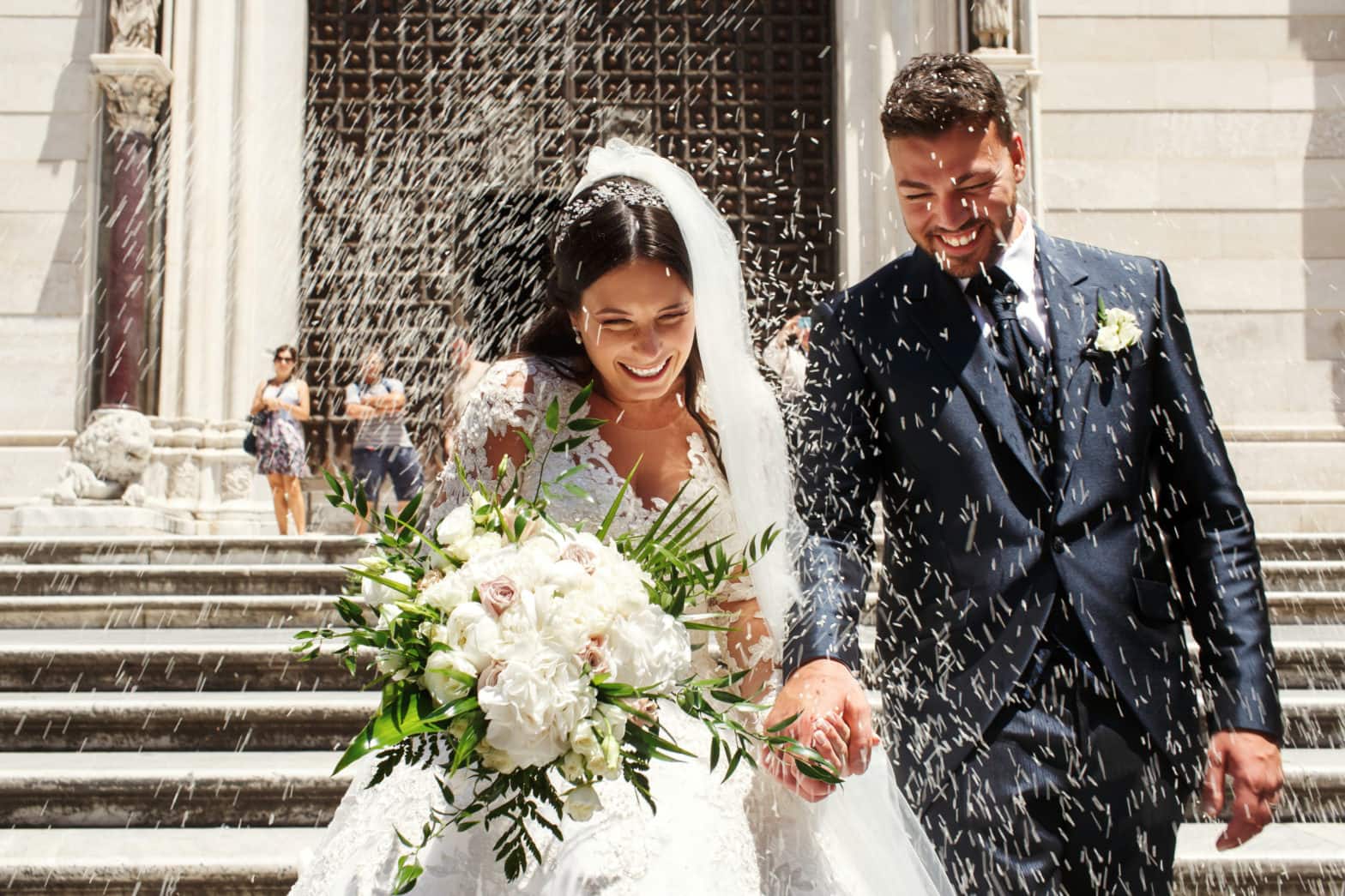 people throw rice on newlyweds walking out of the church