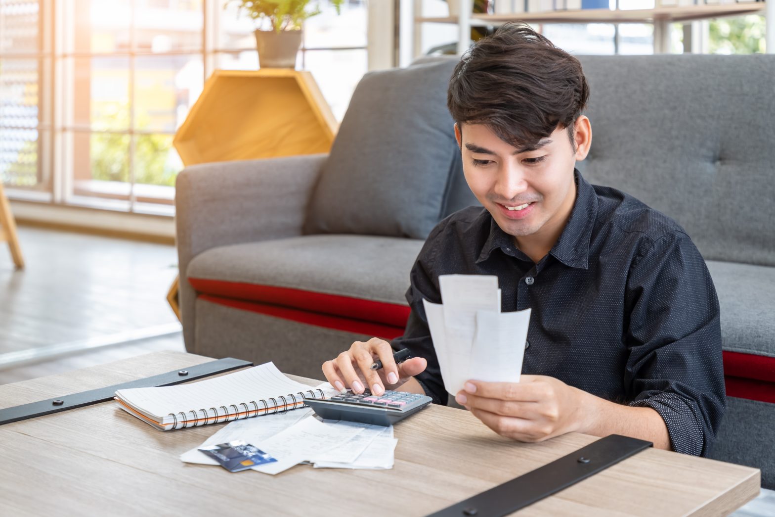 asian man holding bill and calculating tax return