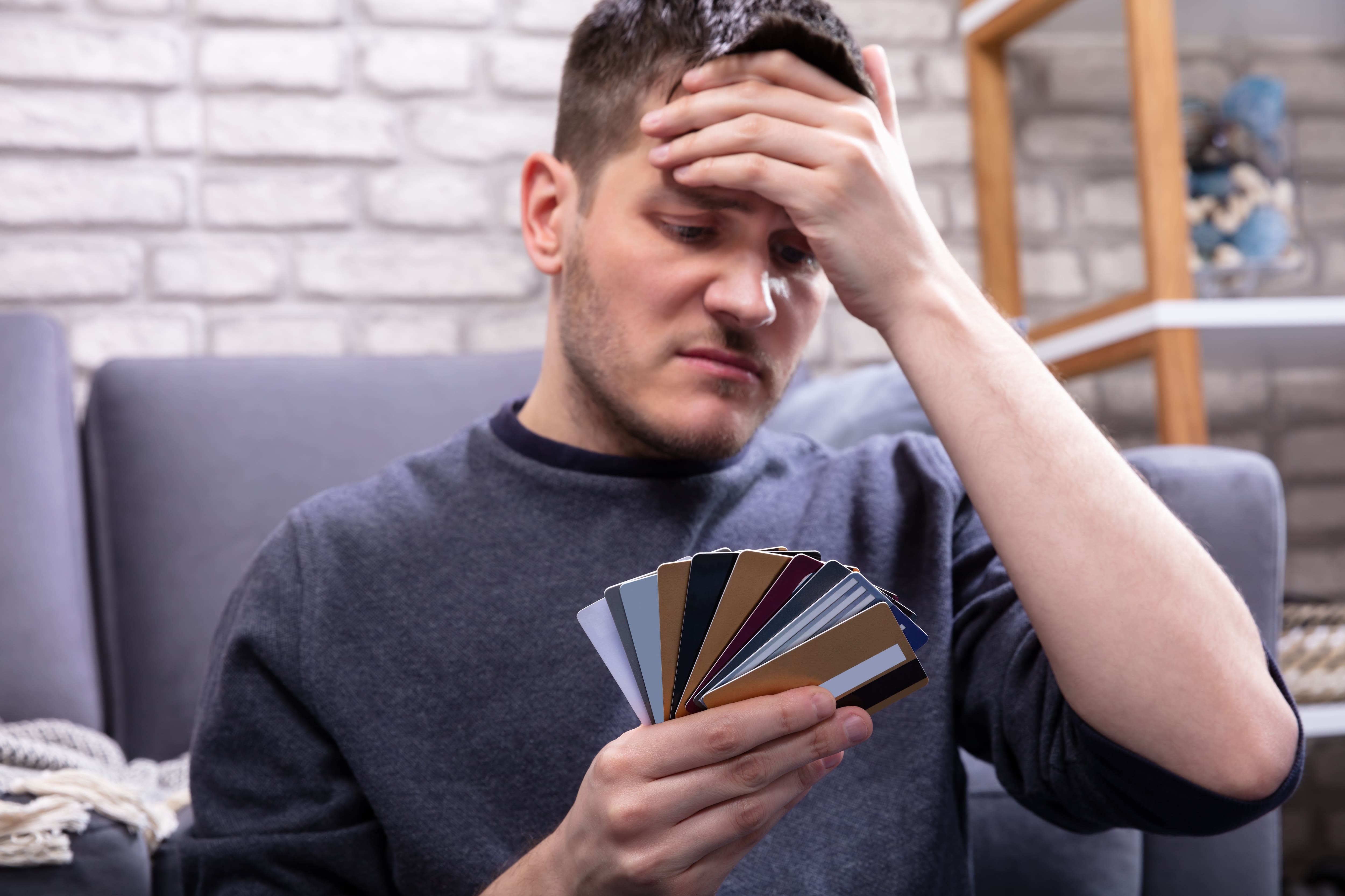 stressed man looking at too many credit cards