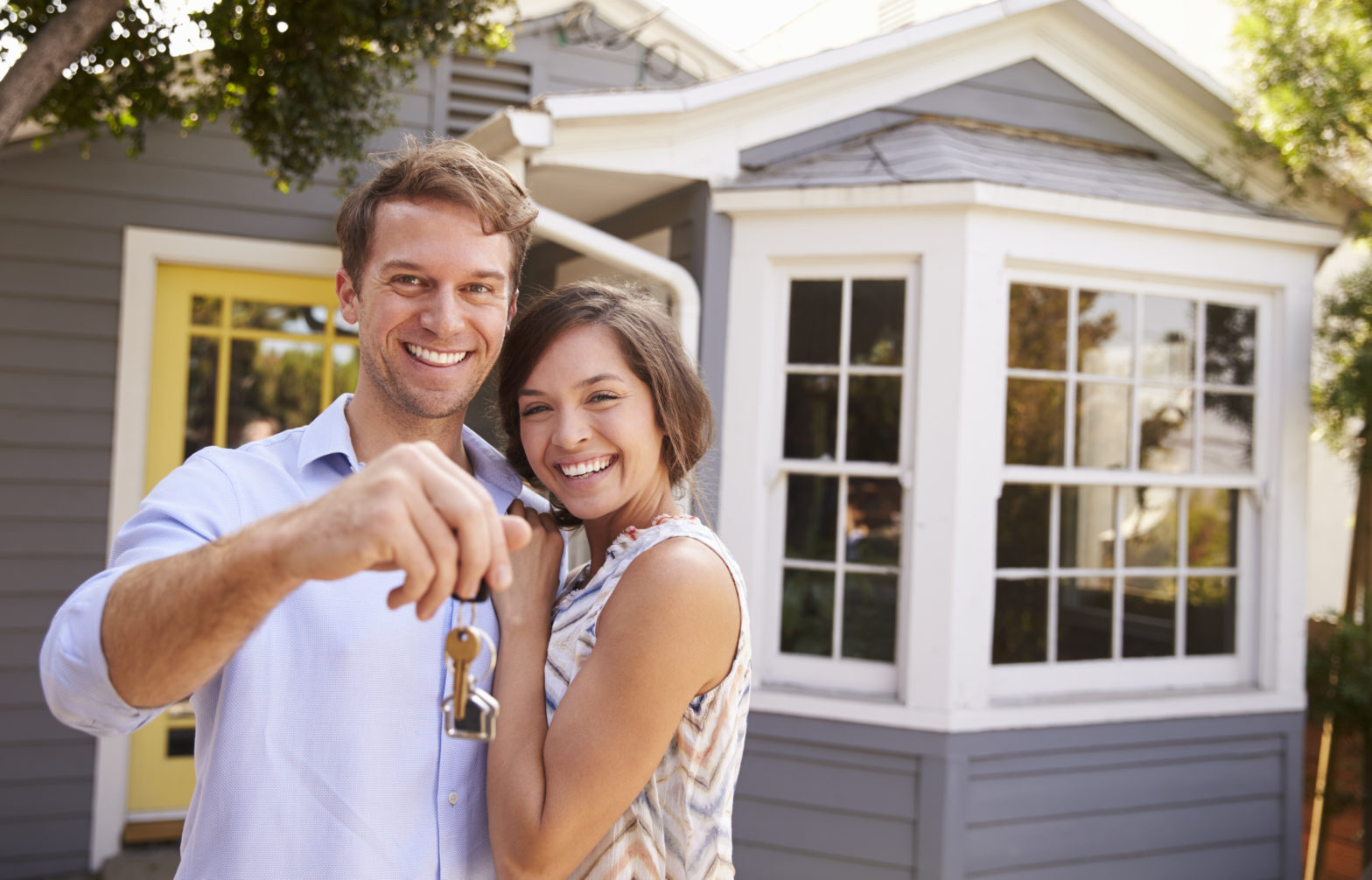 couple with keys standing outside home