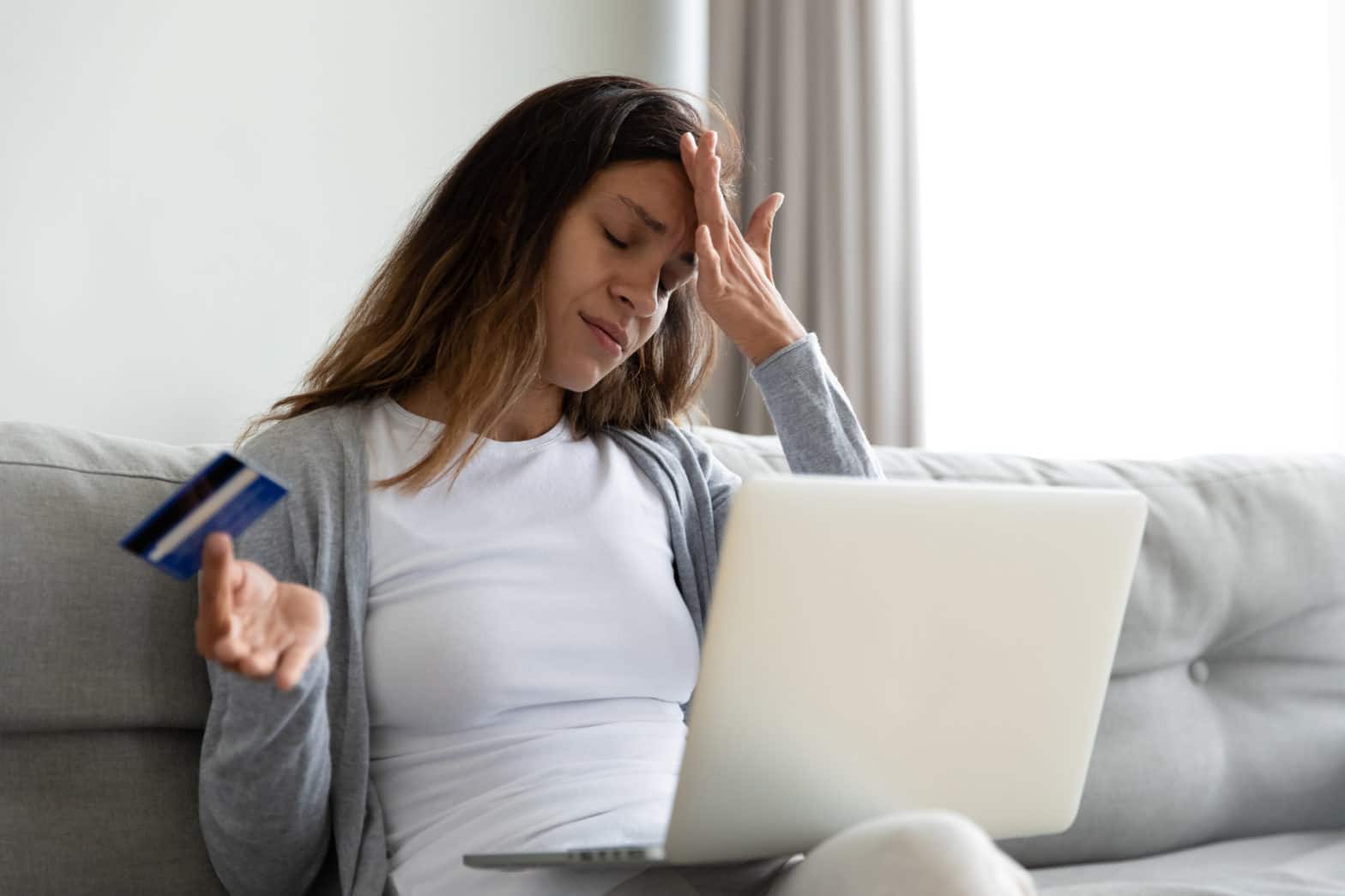 woman sitting on the sofa feels stressed due to a maxed-out credit card