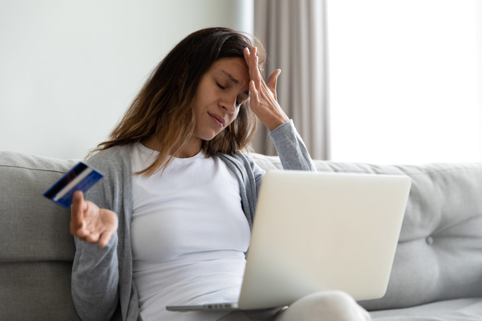 woman sitting on the sofa feels stressed due to a maxed-out credit card