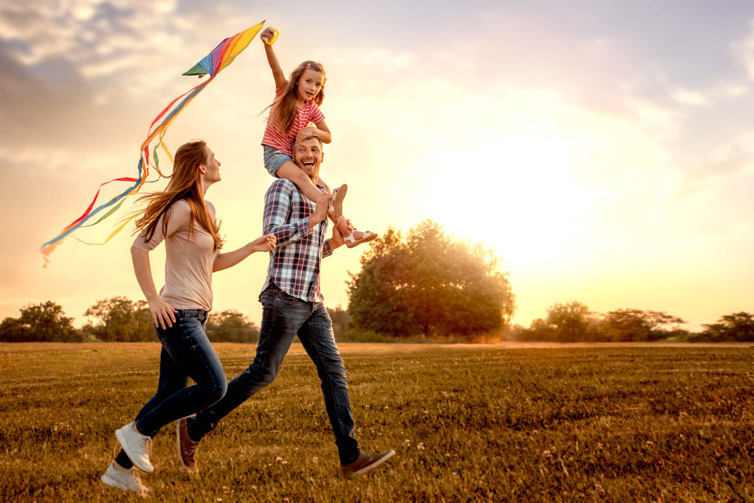happy family running through field letting kite fly