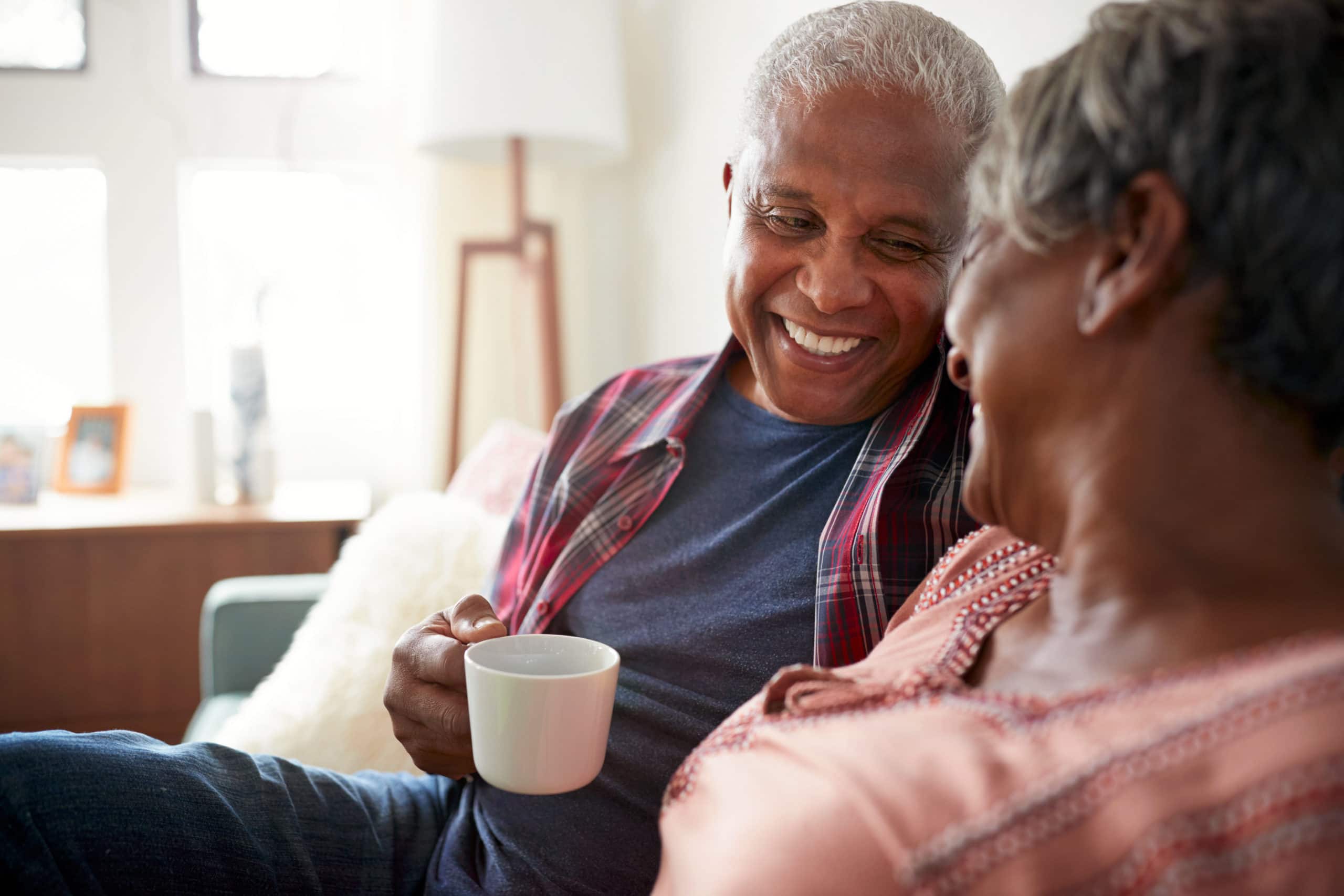 Senior couple smiling and discussing retirement plan holding a coffee cup