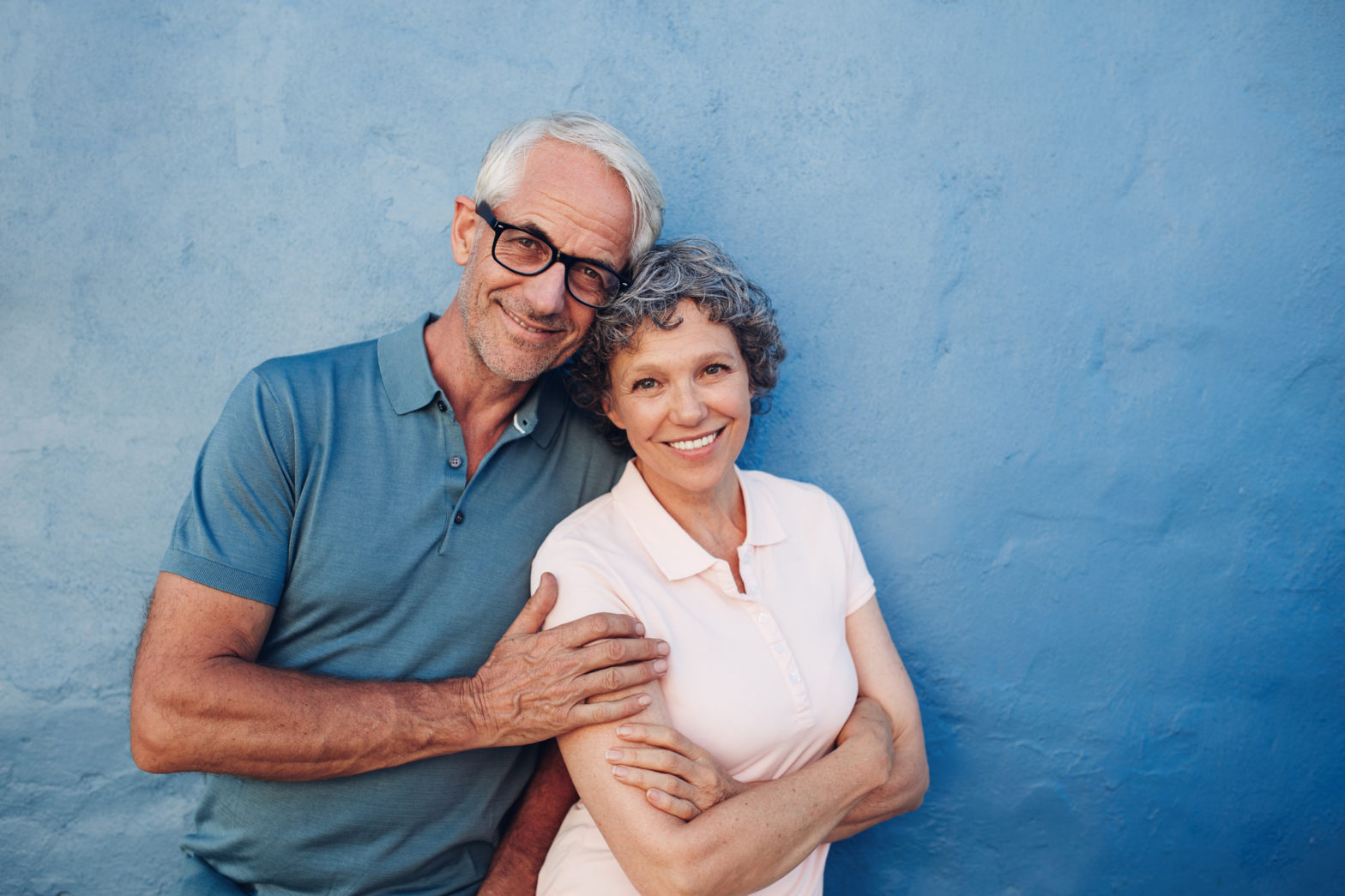 A middle-aged man and woman are front-facing and smiling while looking at camera