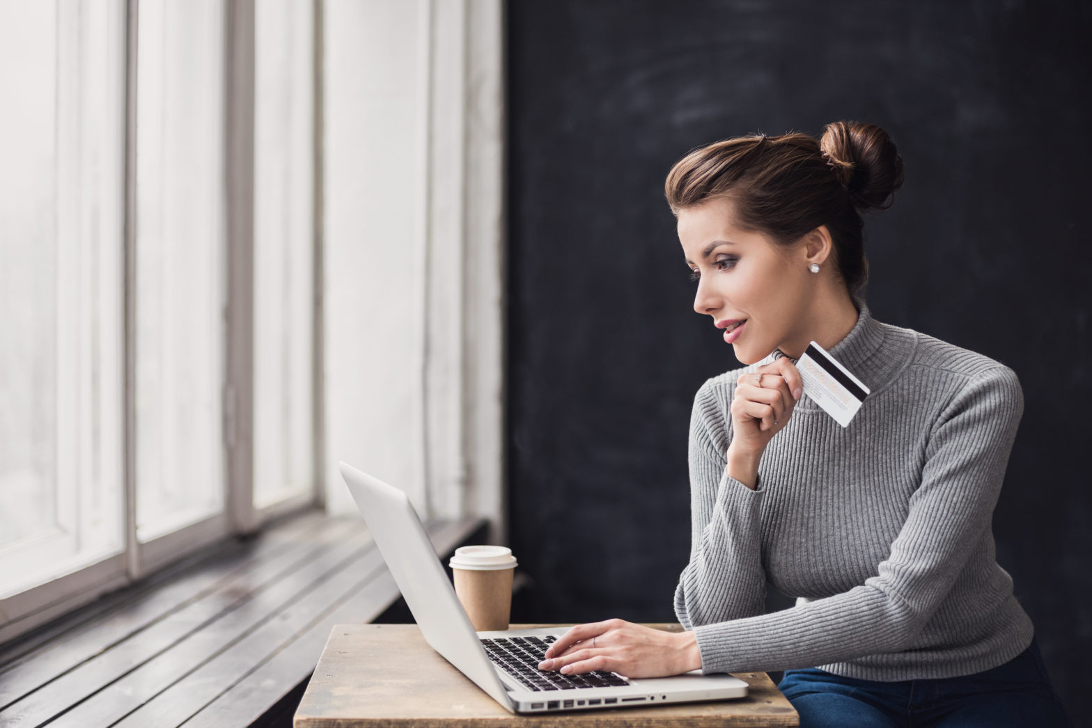 woman holding balance transfer credit card and using laptop