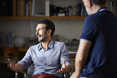 A man discusses investment opportunities with coworkers