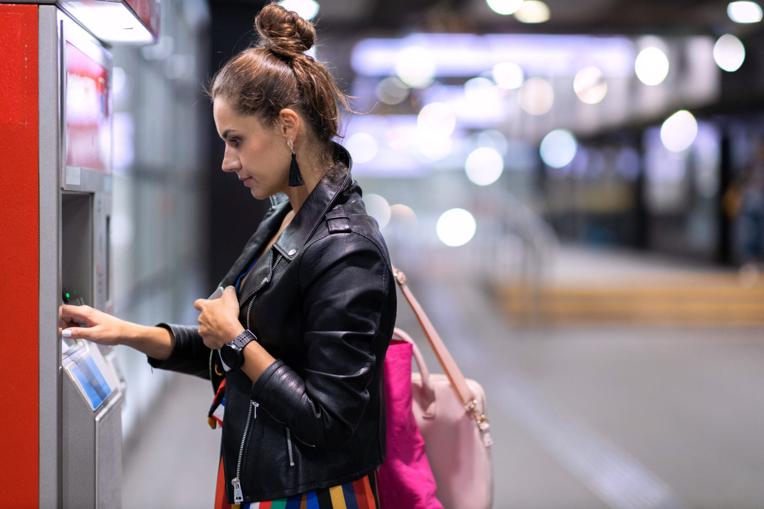 A woman uses an ATM to withdraw money from her account