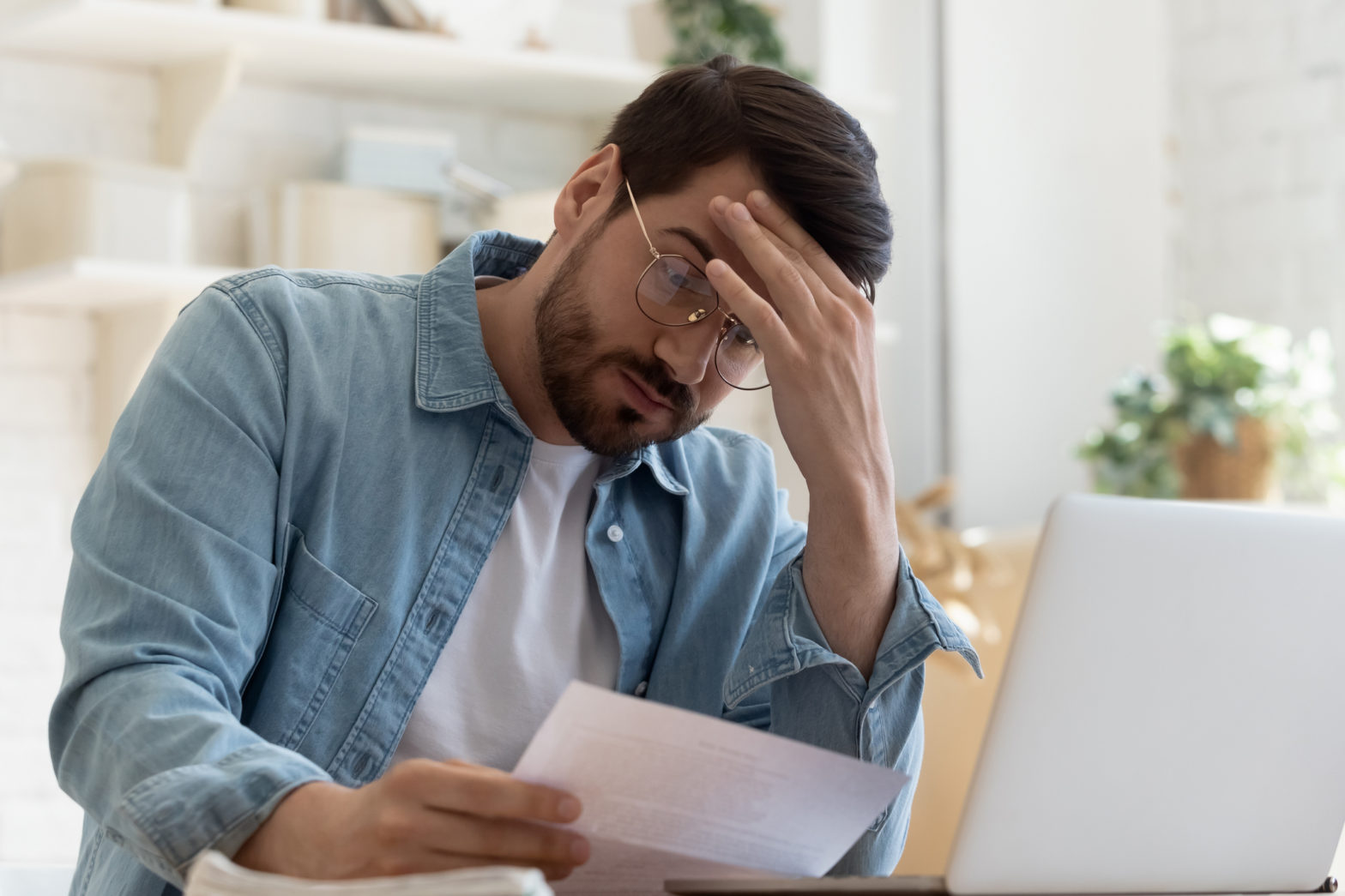 A man looks at a bill with a frustrated look on his face.