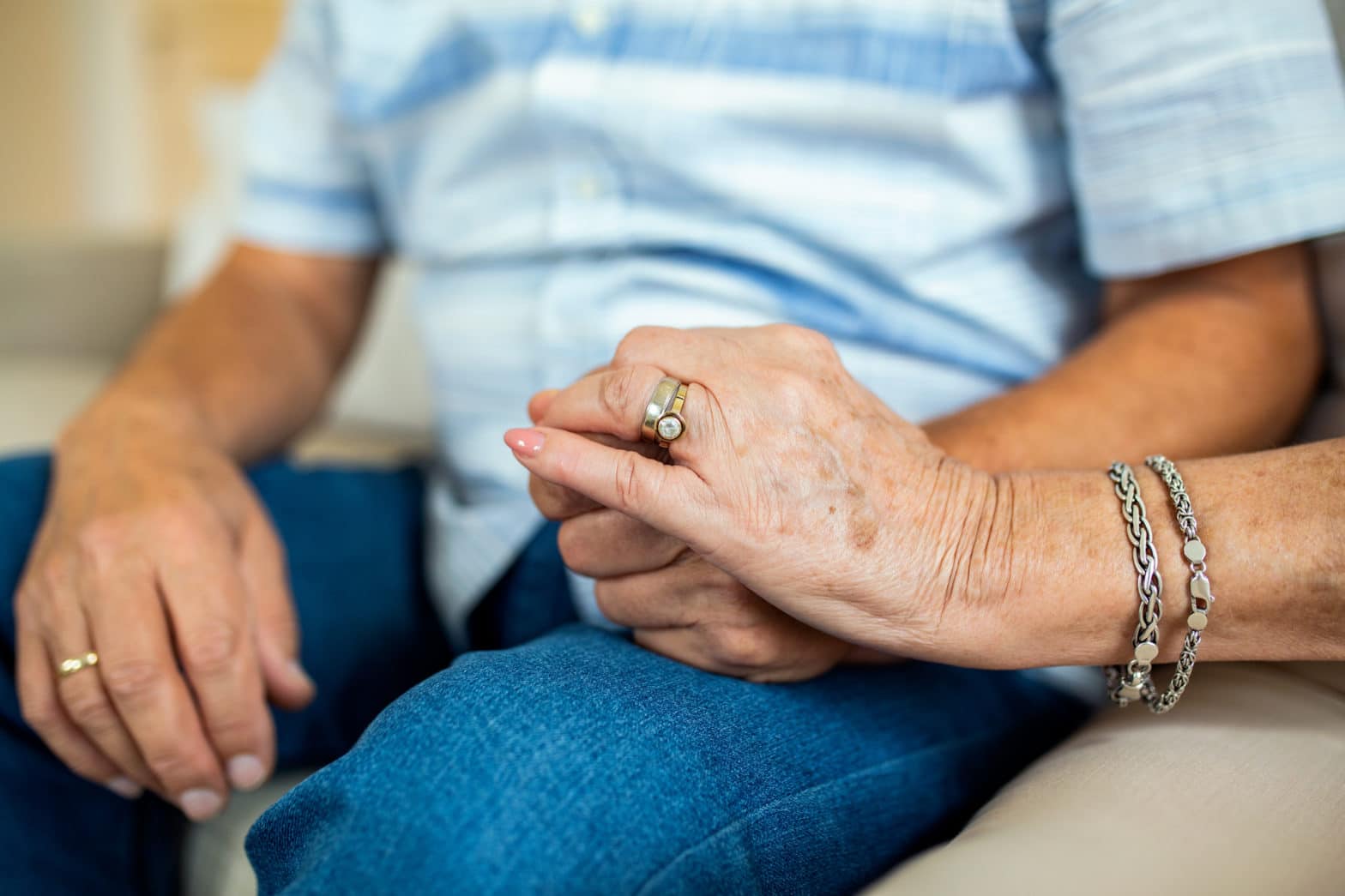 A retired couple hold hands close up