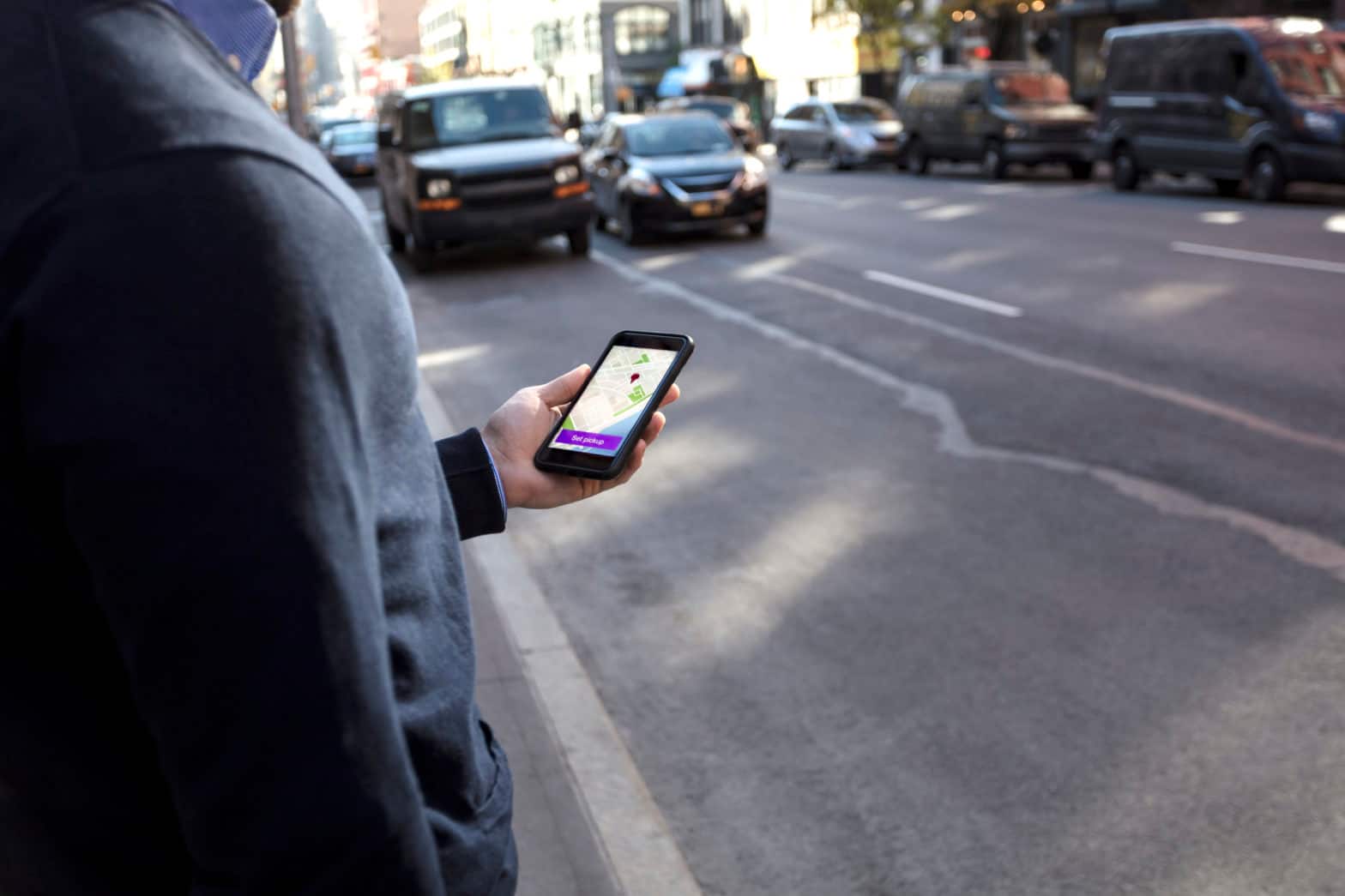 A man looks at his cell phone while standing on a busy street
