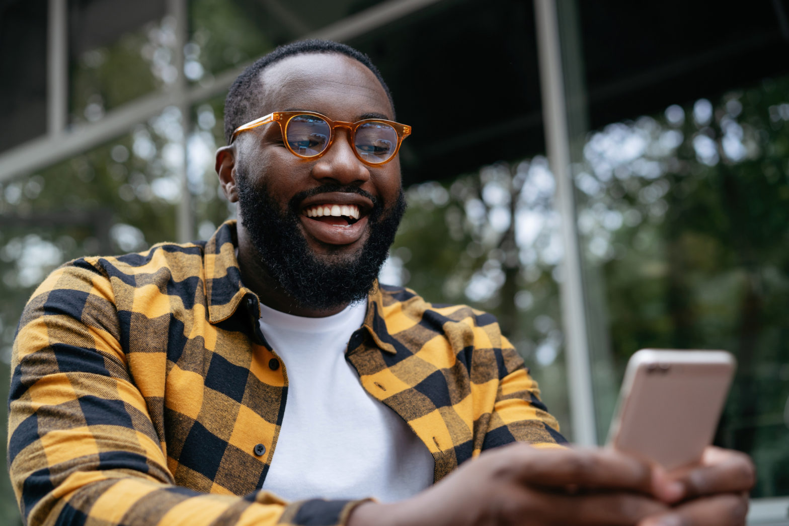 A man checks his stock and cryptocurrency investments on his cell phone with a big smile on his face