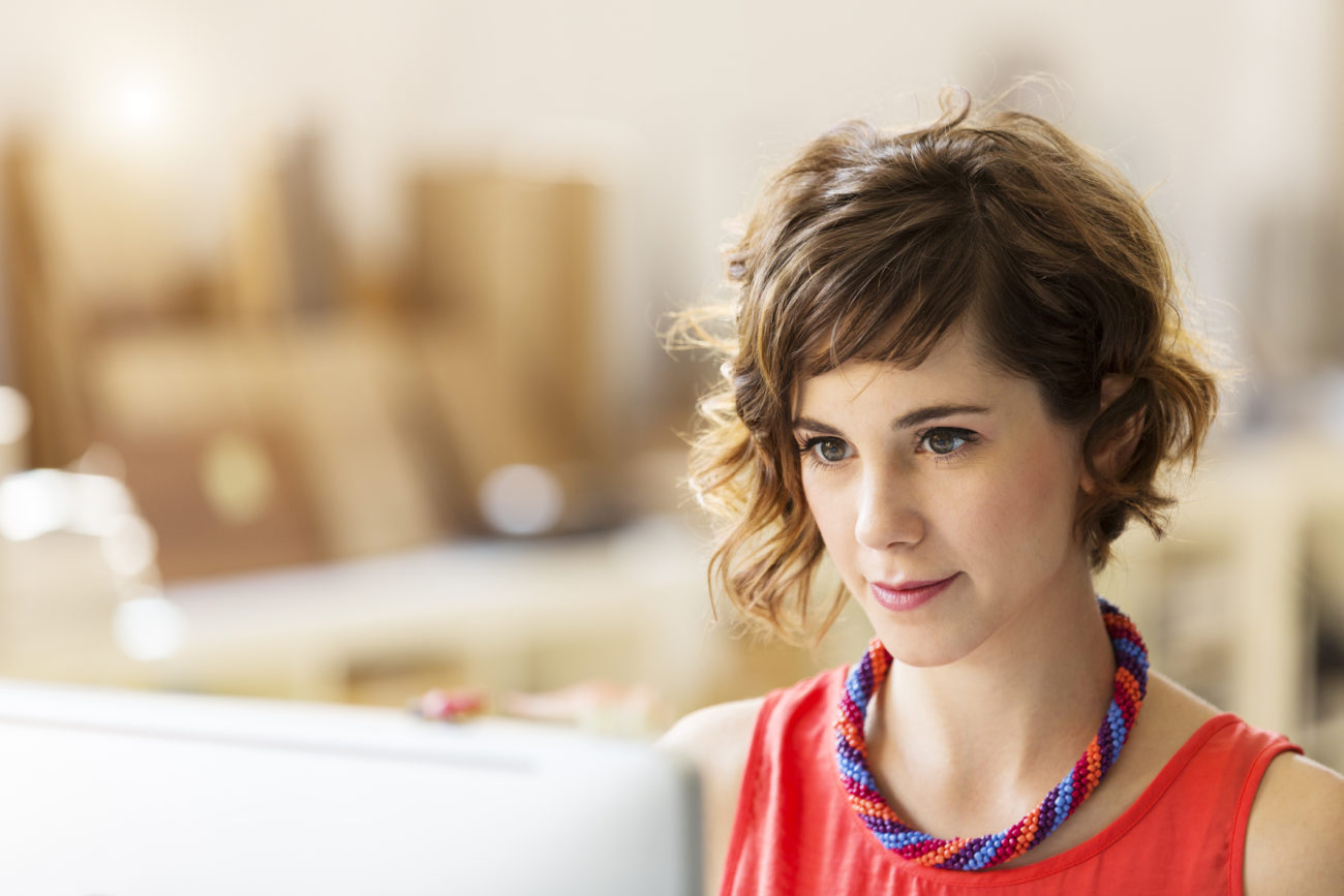 A young, professional woman uses her computer to do her banking online.