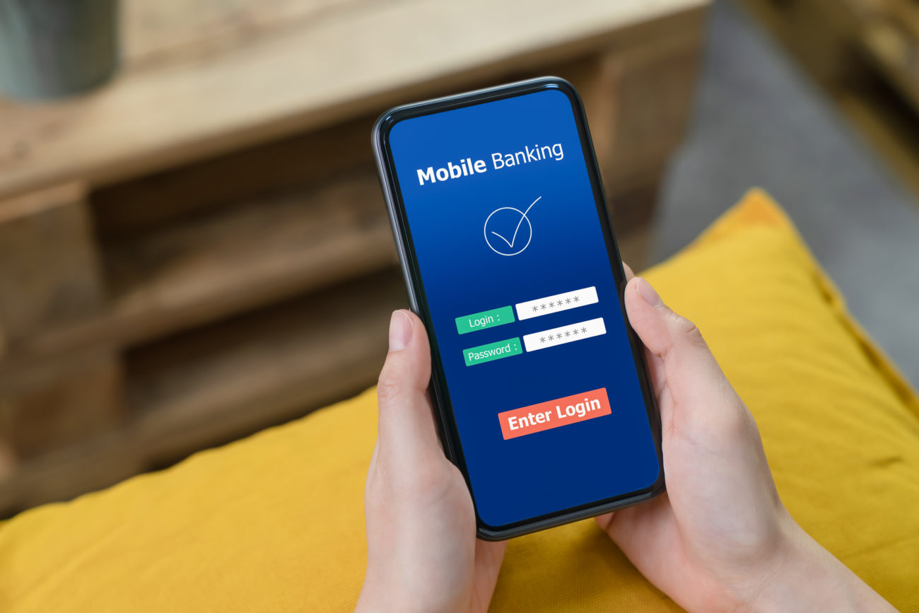 A woman's hands hold a smartphone while she logs onto her bank account app