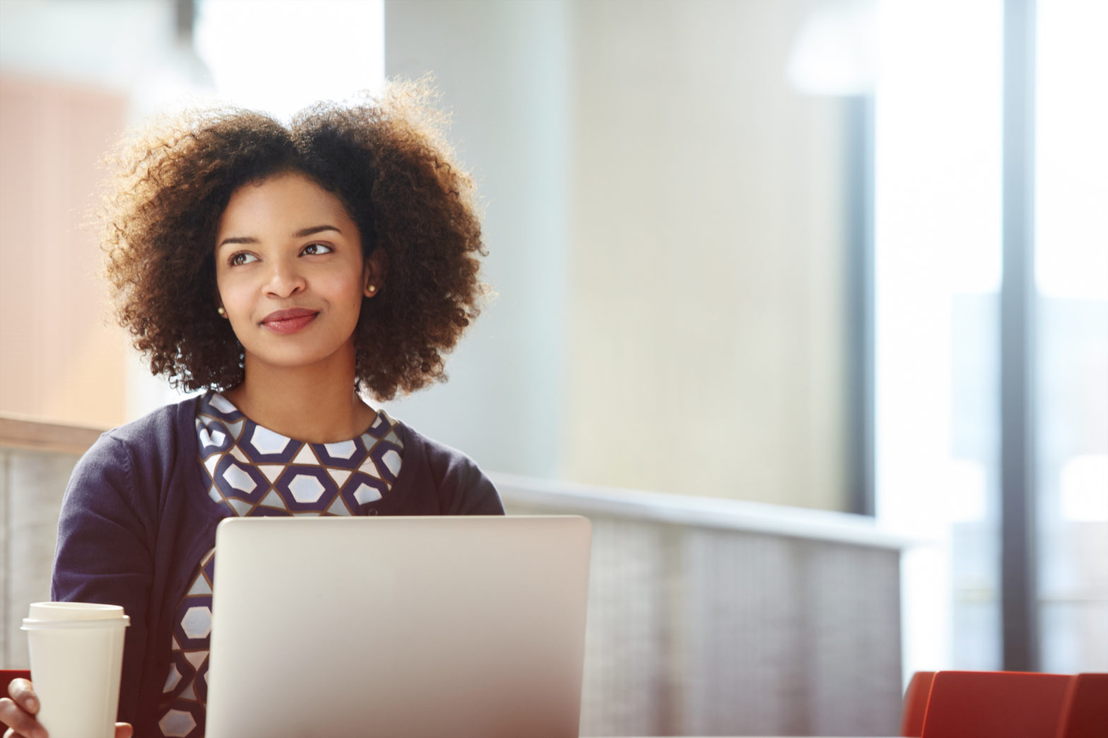 A young business woman sit at a desk in a modern office in front of her computer