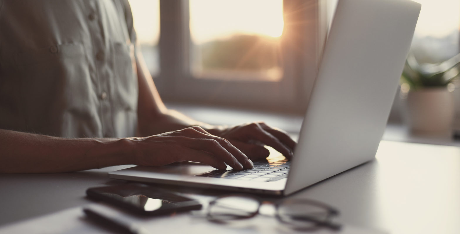 Hands type on a laptop computer while doing online banking