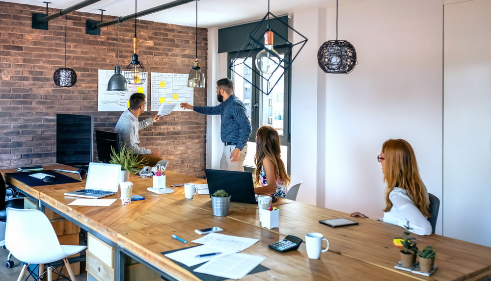 Employees of a startup company are shown strategizing in a modern office space