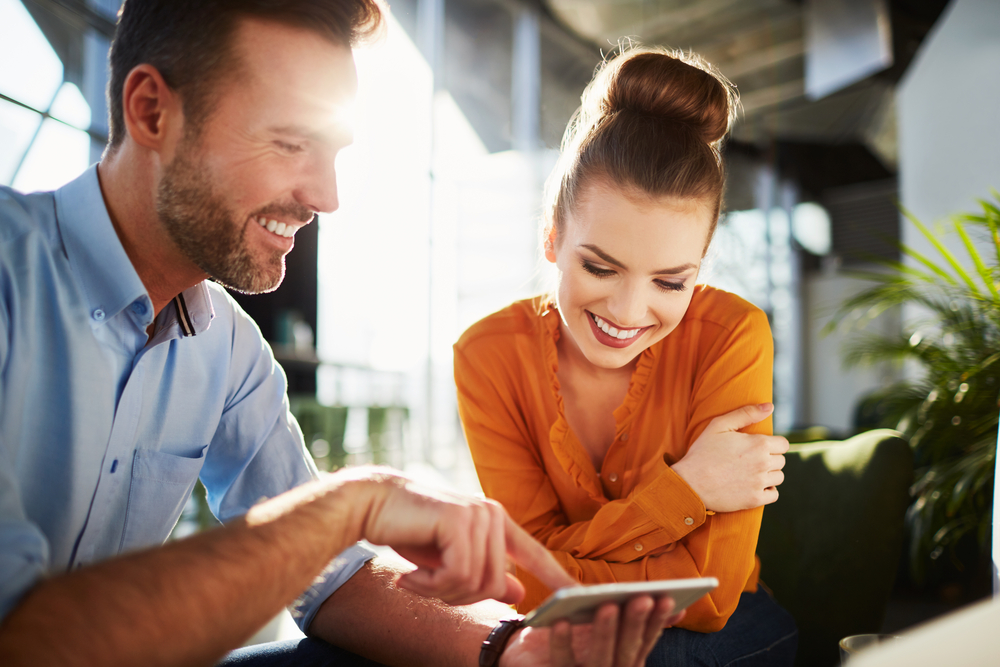 A young couple look at a cell phone in a cafe