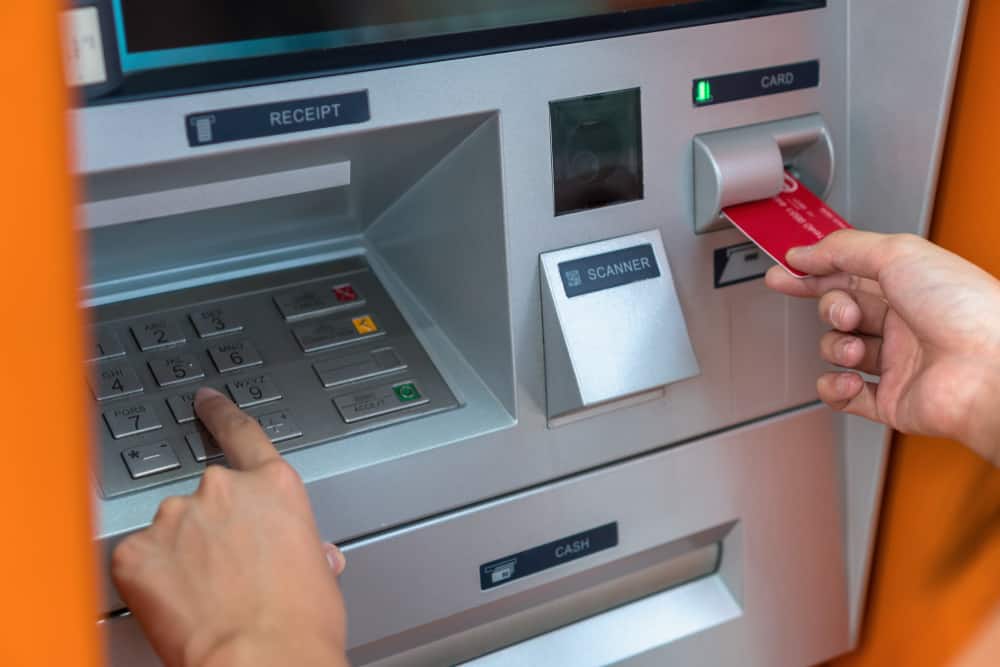 A woman uses her debit card to withdraw money from an ATM