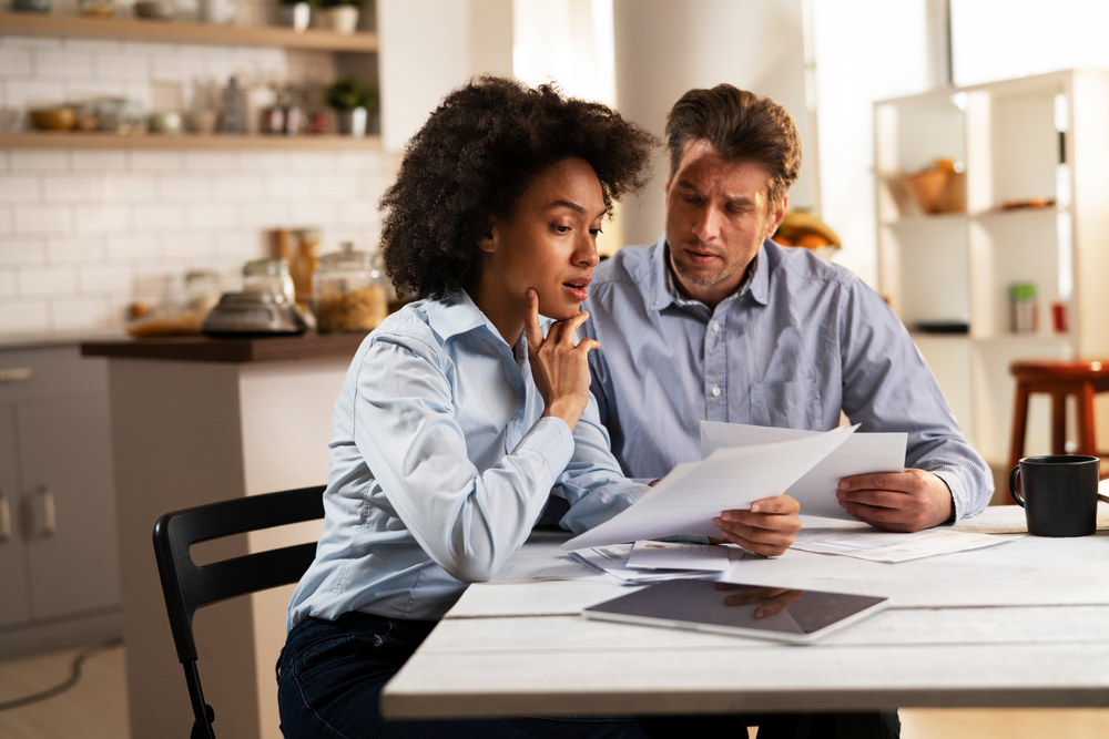 A young couple sitting at the kitchen table working on their taxes