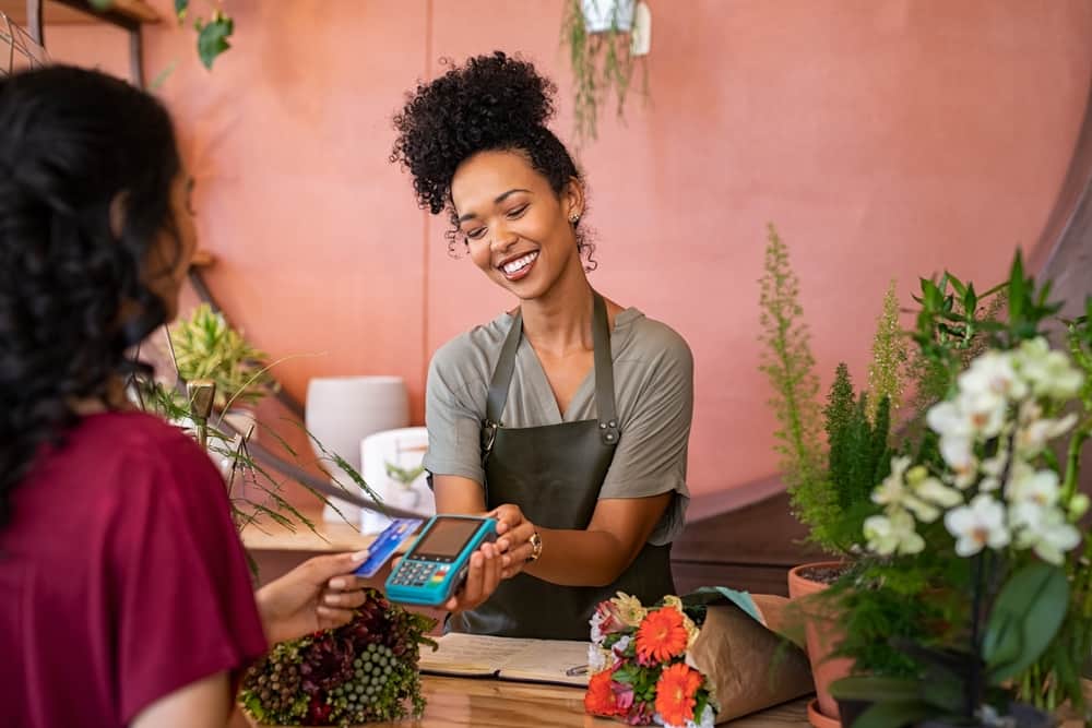 A small business owner accepts a credit card at her florist business