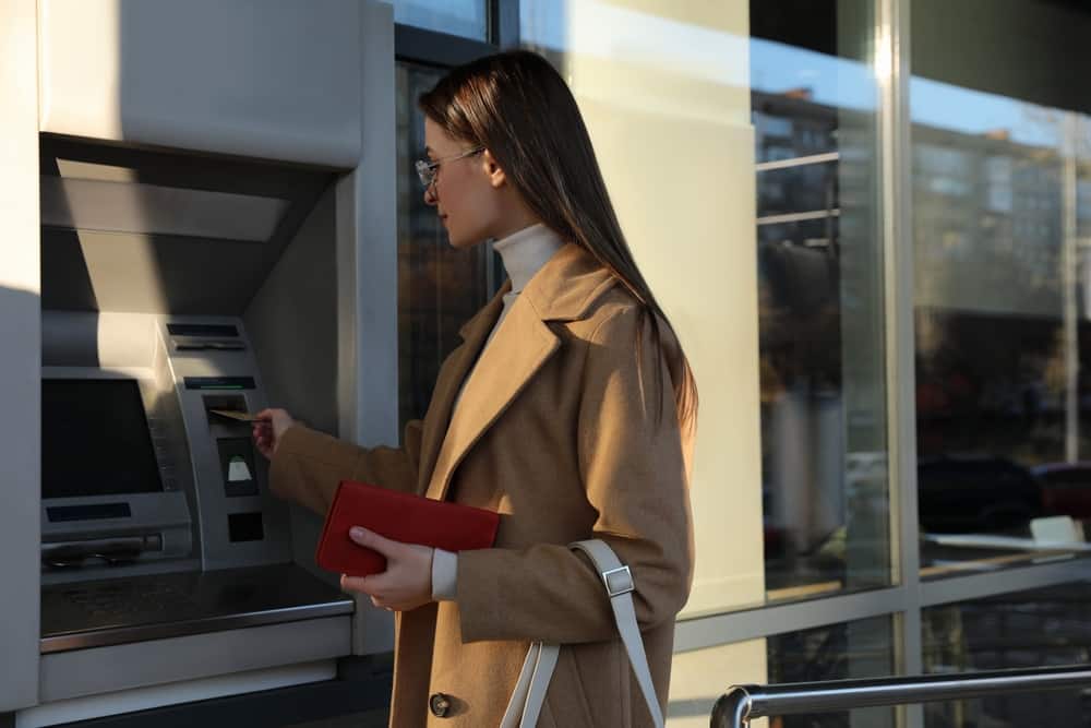 A woman uses a cash machine with an ATM card to access her money market account